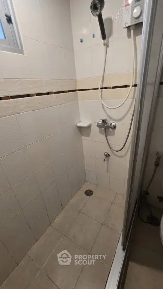 Compact bathroom with shower and tiled walls in modern apartment