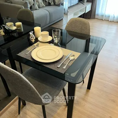 Modern dining area with glass table and elegant place setting in stylish apartment.