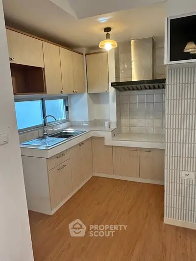 Modern kitchen with wooden cabinets and sleek countertops in a cozy apartment.