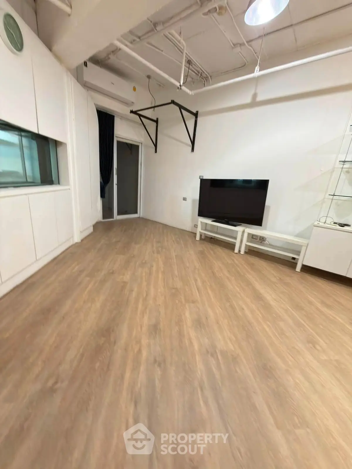 Spacious living room with modern flooring and TV setup, ideal for entertainment and relaxation.