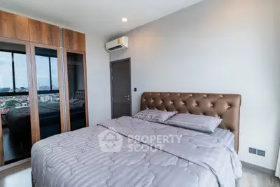 Modern bedroom with city view, featuring stylish bed and mirrored wardrobe in a high-rise apartment.