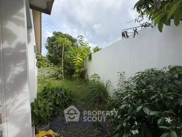 Charming garden space with lush greenery and privacy wall, perfect for relaxation.