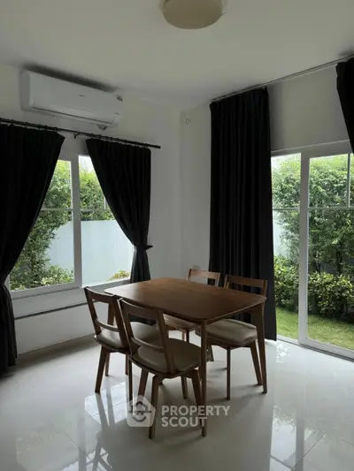 Bright dining area with garden view, featuring modern wooden table and chairs, large windows, and elegant curtains.