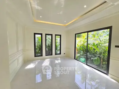 Spacious and bright living room with large windows and garden view, perfect for relaxation and entertaining.