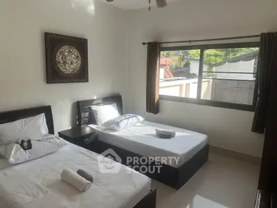 Bright twin bedroom with large window and modern decor, perfect for a cozy stay.