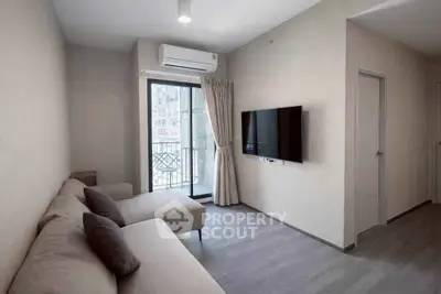 Modern living room with sleek design, featuring a wall-mounted TV and access to a small balcony.