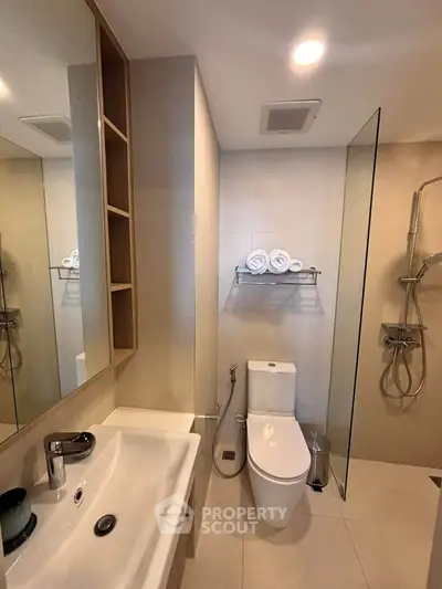 Modern bathroom with sleek fixtures and glass shower enclosure in a contemporary apartment.