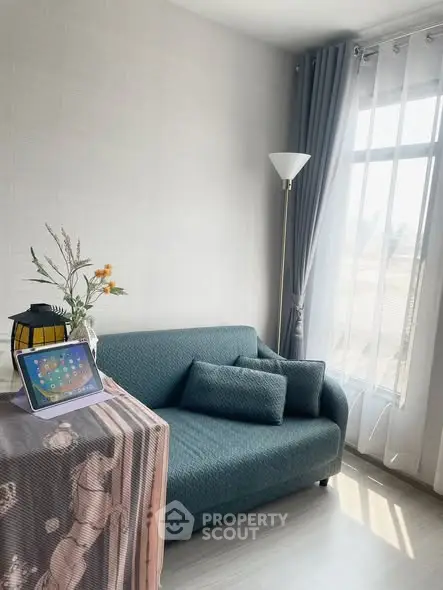 Cozy living room with teal sofa and floor lamp by a sunlit window