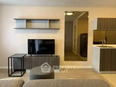 Modern living room with sleek furniture and open kitchen layout, featuring a wall-mounted TV and stylish shelving.