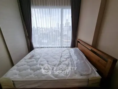 Spacious bedroom with large window offering city views, featuring a comfortable bed and elegant curtains.