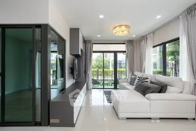Modern living room with elegant decor and large windows offering garden views.