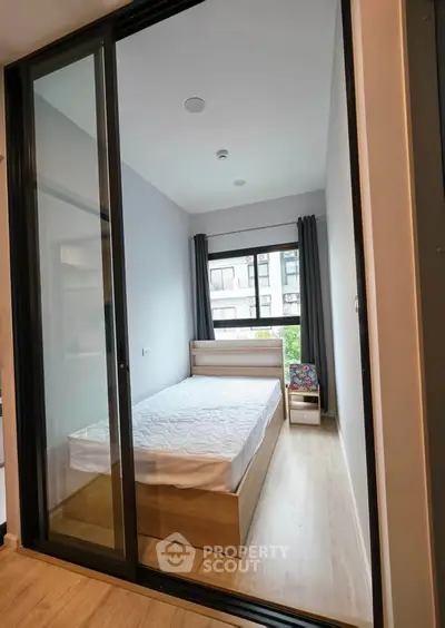 Modern bedroom with large window and sliding glass doors in urban apartment