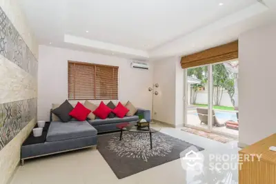 Spacious living room with modern decor, large sectional sofa, and pool view through sliding glass doors.