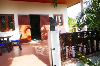 Charming patio with wooden furniture and lush greenery, perfect for outdoor relaxation.