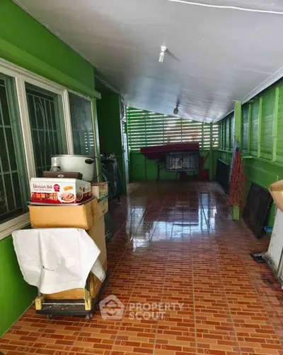 Spacious covered balcony with tiled flooring and green walls, ideal for outdoor relaxation.