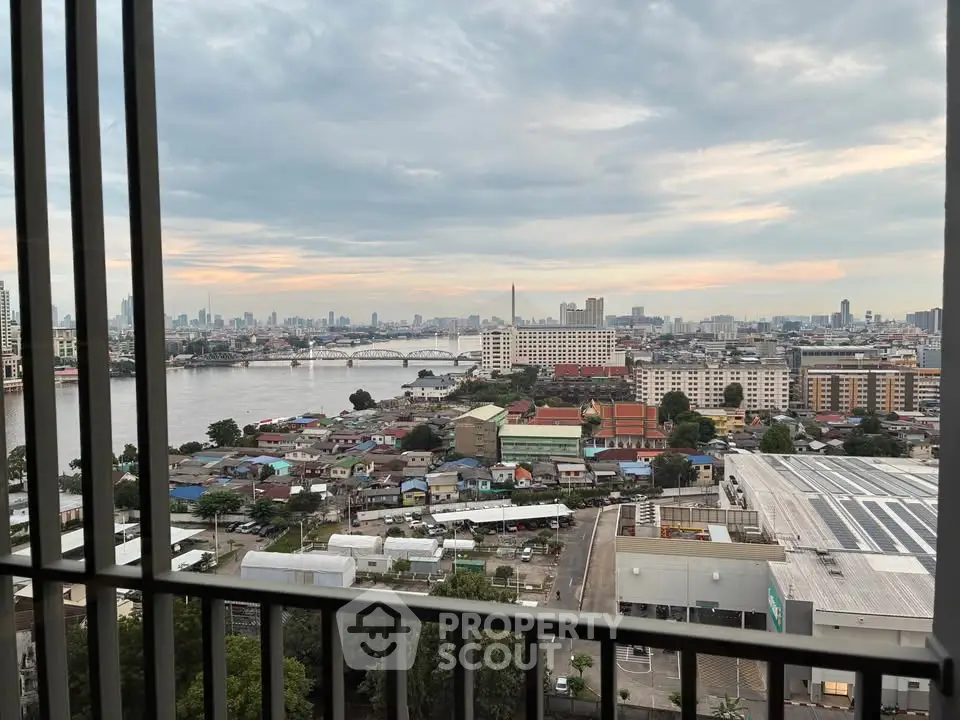 Stunning cityscape view from a high-rise balcony overlooking a river and urban skyline.