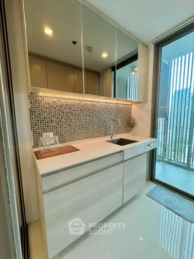 Modern kitchen with sleek design and balcony view, featuring stylish backsplash and ample storage.