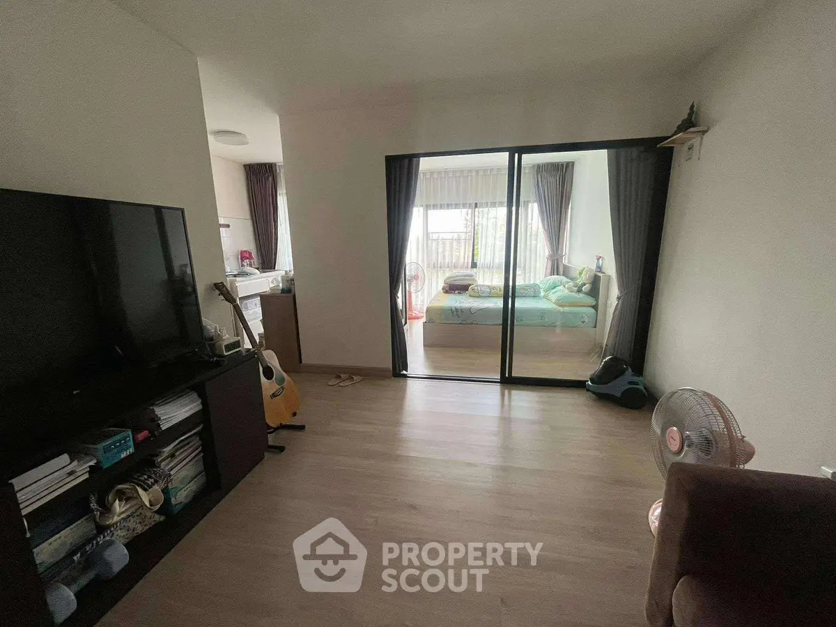 Spacious living room with sliding doors leading to a cozy bedroom, featuring modern decor and ample natural light.