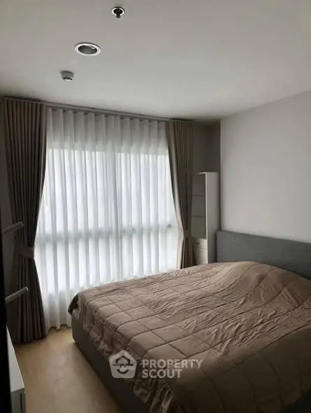 Cozy bedroom with large window and elegant curtains in modern apartment.