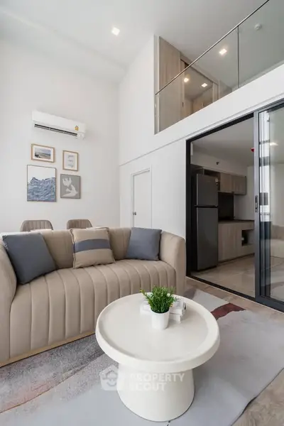Modern living room with loft, stylish sofa, and open kitchen layout