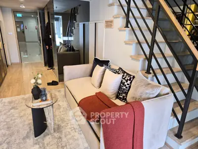Modern living room with stylish staircase and cozy sofa in a contemporary apartment.