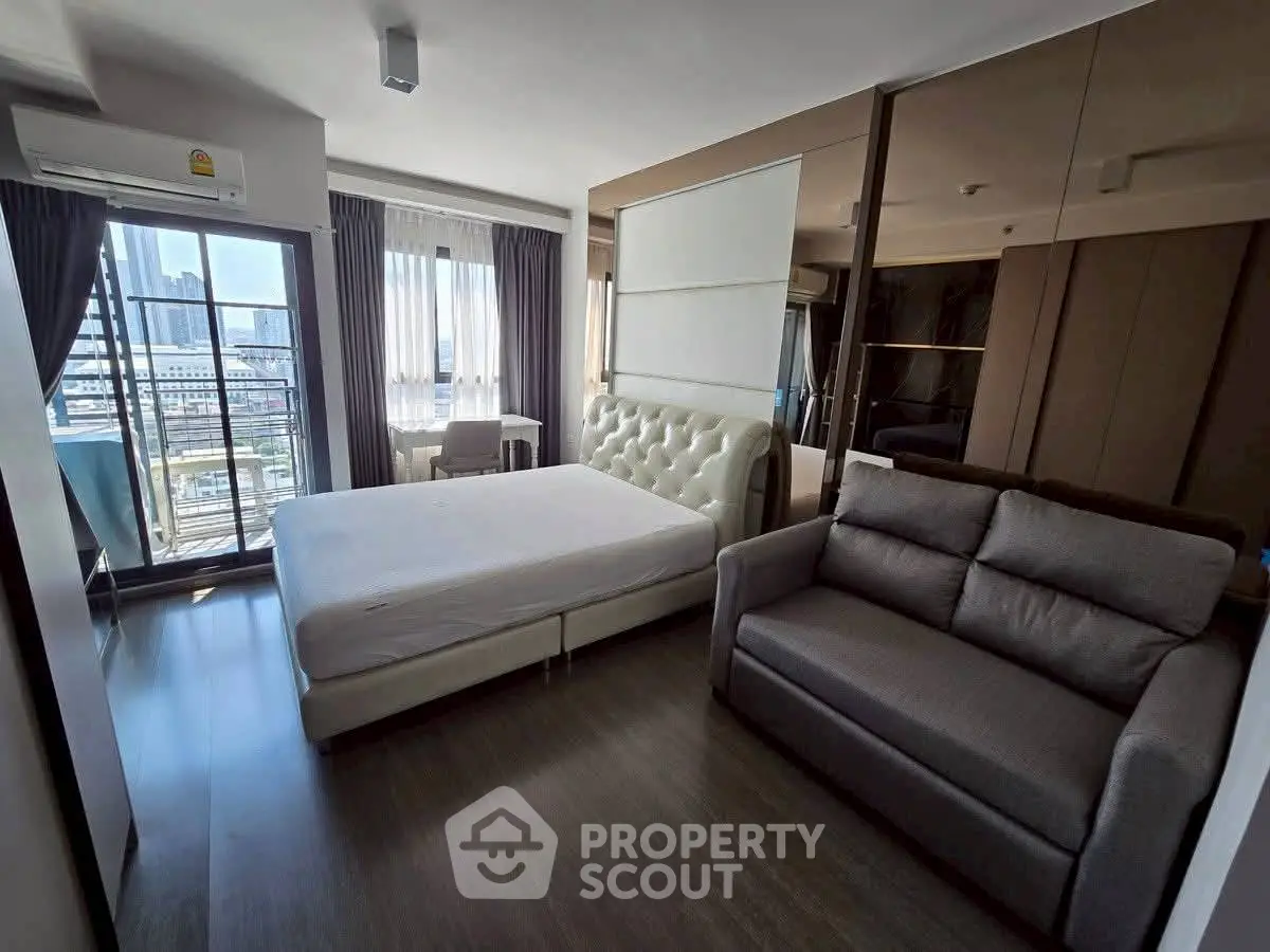 Modern bedroom with city view, featuring a plush bed and cozy sofa, perfect for urban living.