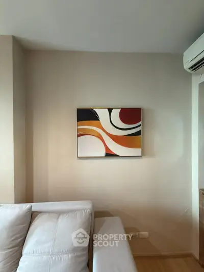 Modern living room with abstract art and sleek white sofa, featuring air conditioning for comfort.