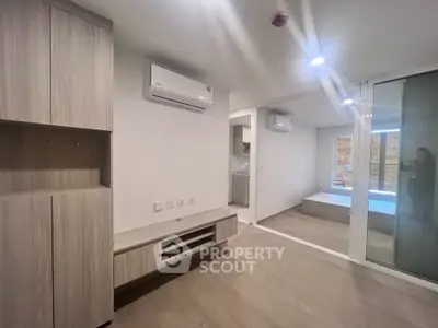 Modern apartment interior with sleek wood flooring and built-in storage, featuring air conditioning and a cozy bedroom.