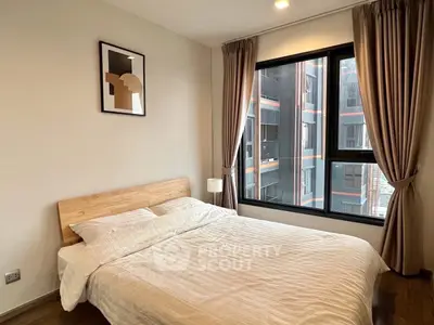 Cozy bedroom with modern decor and large window offering urban view