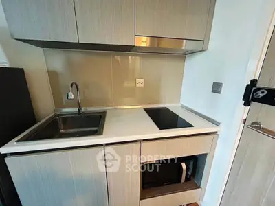 Compact modern kitchen with sleek cabinetry and built-in appliances in a stylish apartment.