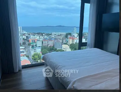 Luxurious bedroom with stunning ocean view from high-rise window, perfect for serene living.