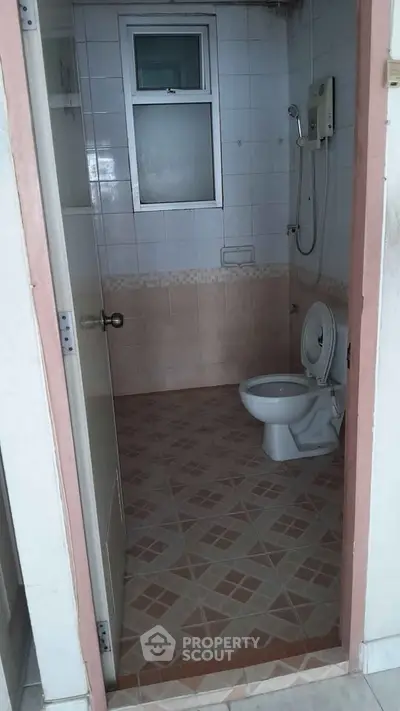 Compact bathroom with tiled floor and wall-mounted shower in a real estate property.