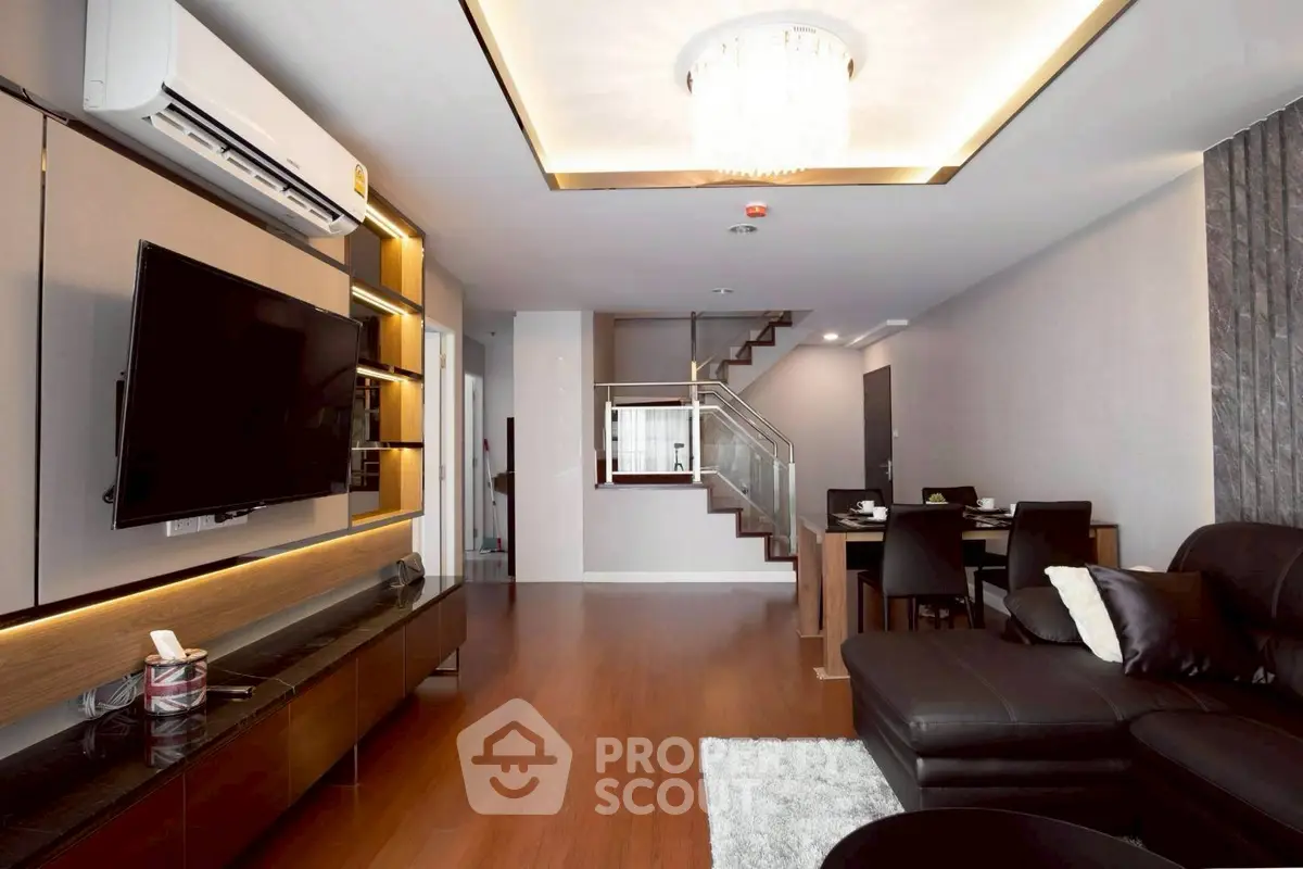 Modern living room with sleek design, featuring a large TV and stylish lighting.