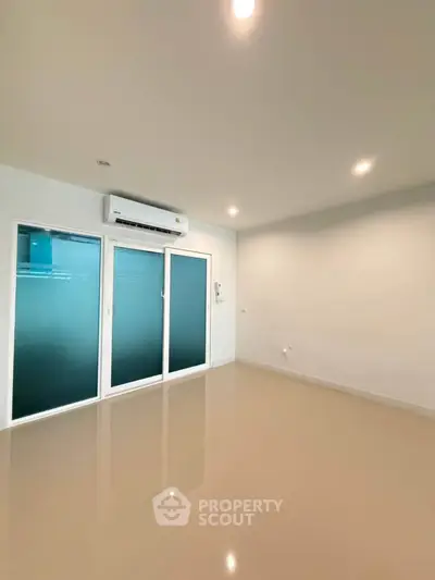 Spacious empty room with glossy floors and air conditioning, ideal for customization.