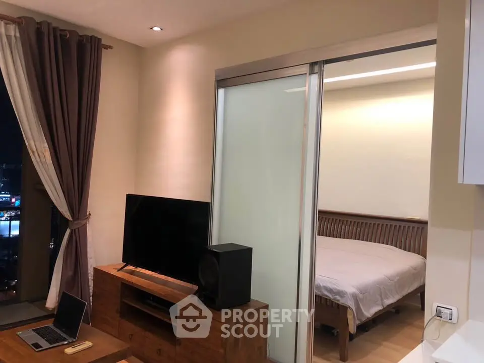 Modern apartment interior with cozy living room and bedroom, featuring wooden furniture and large window view.