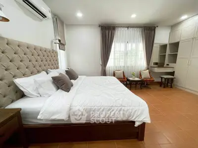 Spacious bedroom with elegant decor and natural light, featuring a cozy seating area and ample storage.