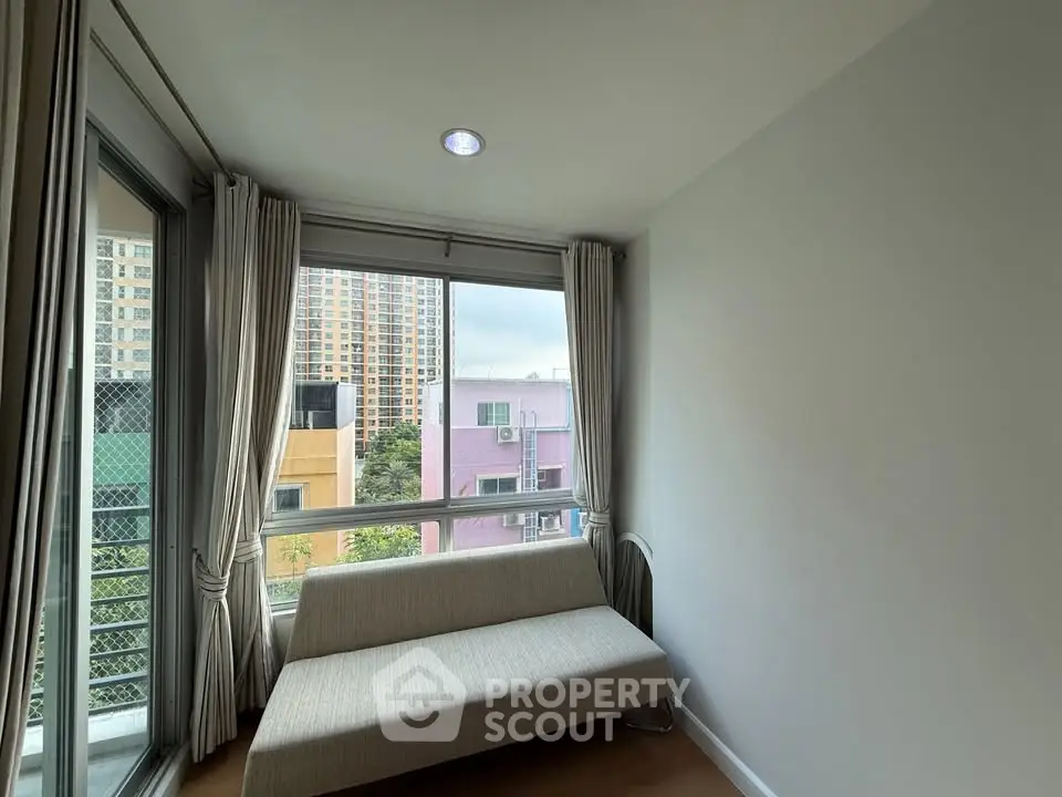 Bright corner unit with large windows and city view, featuring a cozy sofa and modern curtains.