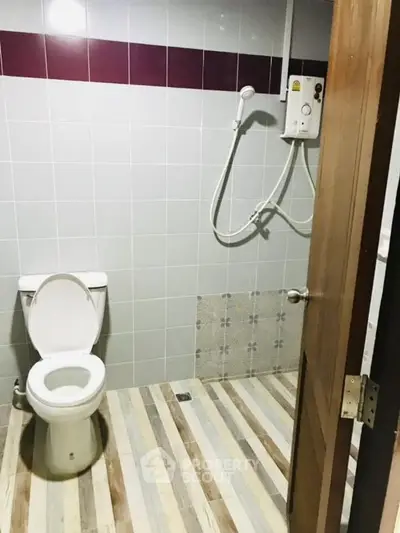 Modern bathroom with tiled walls and electric shower in a real estate property.