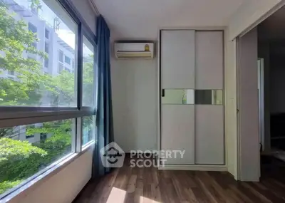 Bright room with large window and air conditioning, featuring a sliding door wardrobe and wooden flooring.