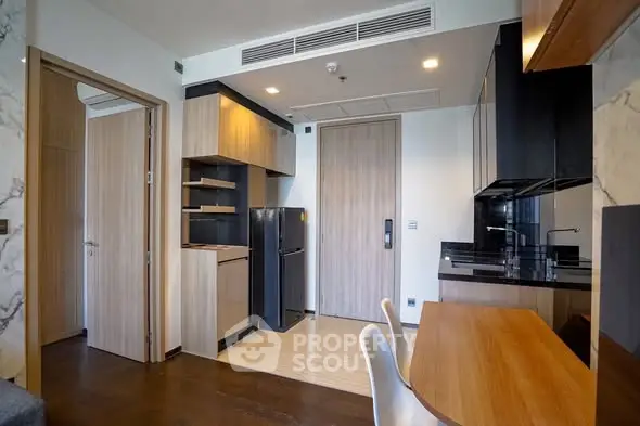 Modern apartment interior with sleek kitchen and dining area, featuring wood and black accents.