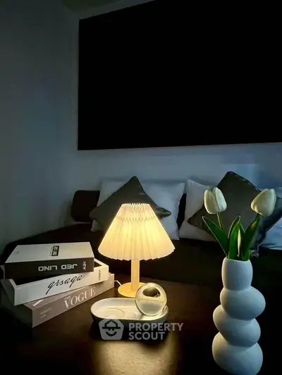 Cozy living room with stylish decor, featuring a modern lamp, elegant vase with tulips, and designer books.