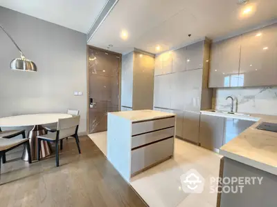 Modern kitchen with sleek white cabinetry and marble countertops, complemented by warm wooden flooring and elegant dining area.