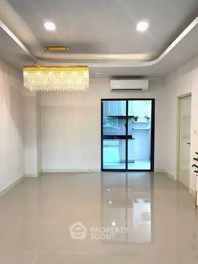 Spacious modern living room with elegant chandelier and large window view.