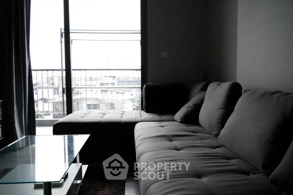 Modern living room with stylish gray sofa and glass coffee table, offering a cozy and inviting atmosphere.