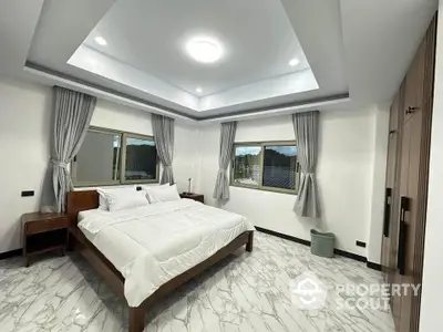 Spacious modern bedroom with elegant decor and large windows offering natural light.