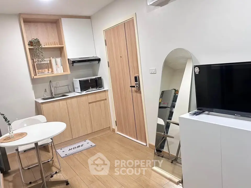 Chic compact kitchen with modern appliances and cozy dining area in stylish apartment.