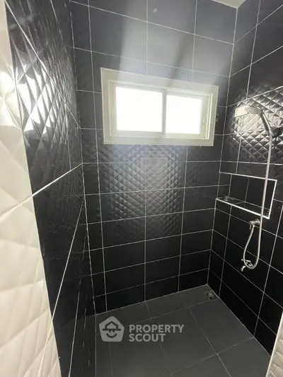Modern bathroom with sleek black tiles and a window for natural light.