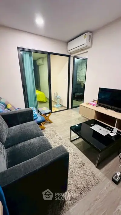 Modern living room with cozy sofa, TV, and balcony access in stylish apartment.