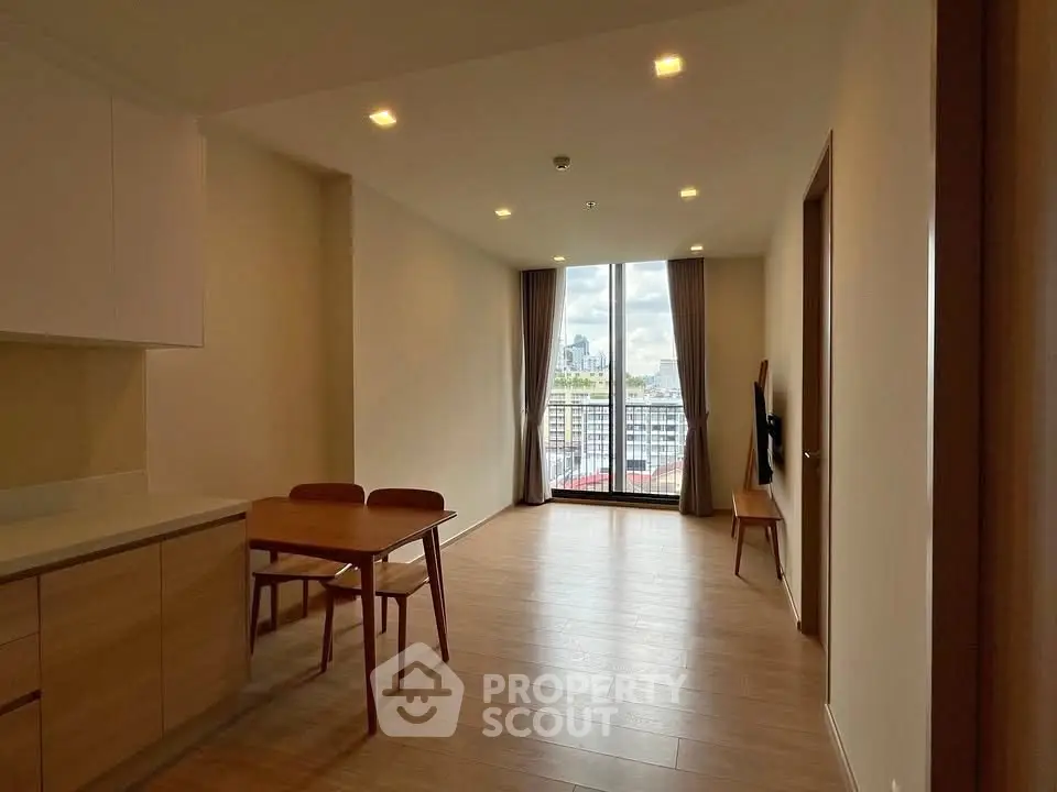 Spacious living room with wooden flooring and city view from large window.