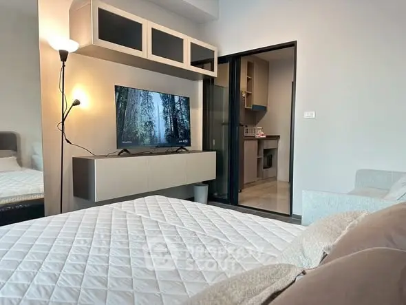 Modern studio apartment with cozy bed and sleek TV setup